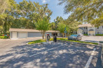 View of Enclave at Pine Oaks Apartments parking area featuring shaded trees and modern facilities.
