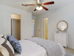 Cozy bedroom featuring a ceiling fan, spacious layout, and natural light in an apartment.