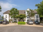 Exterior view of Crosswinds Apartments featuring trees and parking, close to shopping in Pearl, MS.