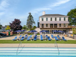 Outdoor pool area at Independence Green Apartments with sun loungers and umbrellas, surrounded by green lawns.