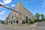 Exterior view of Woolen Mills Lofts in Appleton, WI, showcasing historic urban architecture and greenery.