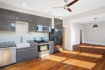 Modern kitchen in 2-bedroom apartment featuring granite countertops, hardwood floors, and stainless steel appliances.