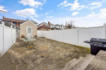 Private rear yard of charming single-family home at 1557 E 34th St, Brooklyn, featuring a patio and white PVC fencing.