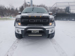 Front view of a lifted 2014 Ford F-150 FX4 in snow, showcasing its rugged design and off-road capabilities.