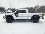 Lifted 2014 Ford F-150 FX4 4WD with aftermarket features and new tires on a snowy background
