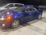 2016 Ford Fusion SE FWD in blue at a gas station, showcasing its modern design and features.