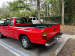 Red 1995 Toyota Tacoma Xtra cab parked, showcasing its original design and well-maintained condition.