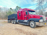 2002 Freightliner Century truck with a dump trailer, showcasing a red exterior in a wooded area.