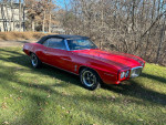 1969 Pontiac Firebird convertible in red, showcasing a classic design on a sunny day.