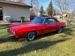 1969 Pontiac Firebird convertible in red color parked on grass with nice paint job and original features.