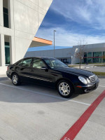 2004 Mercedes-Benz E320 parked outside, showcasing its excellent condition and sleek black exterior.