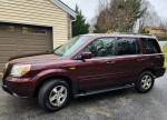 2007 Honda Pilot EX FWD in maroon color parked in front of a garage with a mileage of 132,000 miles.