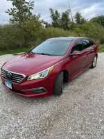 2015 Hyundai Sonata Limited in red color parked on gravel, showcasing its stylish design and features.