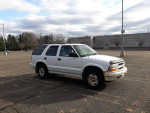 1999 Chevrolet TrailBlazer with 141,000 miles, parked in an empty lot, showing wear and tear.