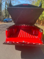 Custom red painted bed of a 1995 Chevrolet S-10 with open cover and design accents.