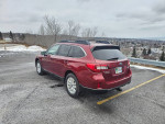 2015 Subaru Outback in a parking lot, featuring a clean black interior and new snow tires.