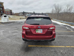 Back view of a 2015 Subaru Outback in a parking lot with snow, showcasing clean design and snow tires.