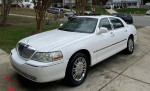 2006 Lincoln Town Car Signature RWD in white with shiny rims, parked on driveway.