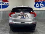 Rear view of a 2018 GMC Terrain SLT FWD, silver SUV, displayed in a showroom setting.