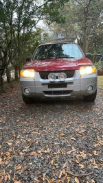 2007 Ford Escape XLT SUV in red and silver parked on gravel, showcasing its front view and headlights.