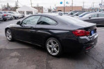 2020 BMW M450i xDrive Coupe in Black Sapphire Metallic parked at dealership, showcasing sleek design and sporty features.