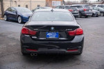 Rear view of a 2020 BMW 430i xDrive Coupe in Black Sapphire Metallic parked in a lot.