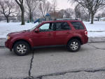 Red Ford Escape parked on a snowy street, showcasing good tires and a clean exterior.