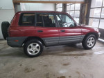 Clean red SUV with low mileage parked indoors, showcasing a neat profile and shiny wheels.