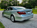 2010 Lexus LS 460 sedan in silver parked on a scenic road with lush greenery in the background.