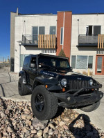 2007 Jeep Wrangler Rubicon 4WD with upgrades parked near a modern building, showcasing its rugged design.