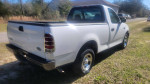 White 2001 Ford F150 regular cab parked on a grassy area, showcasing its sleek design and clean condition.