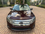 2012 Ford Fusion in raspberry red with low mileage, well-maintained, parked in a scenic location.
