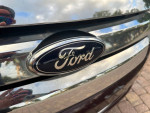 Close-up of the Ford logo on a 2012 Ford Fusion, highlighting its polished chrome and design.
