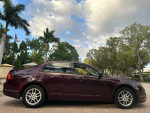 2012 Ford Fusion in raspberry red parked, showcasing polished aluminum wheels and lush greenery in the background