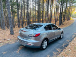 2012 Mazda 3 i Grand Touring parked in a serene forest setting, showcasing a clean exterior and sleek design.
