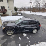 2017 BMW X3 xDrive28i in black parked on snow-covered driveway, displaying minor cosmetic damage.