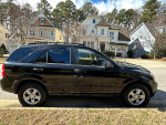 Side view of a 2009 Kia Sorento parked, showcasing its black exterior and new tires.