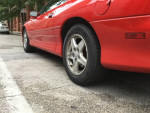 Close-up of a red 1997 Chevrolet Camaro RS showcasing wheels and pristine body condition.
