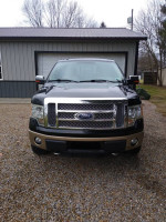 Front view of 2011 Ford F-150 4x4 SuperCrew parked on gravel, showing its distinct grille and smooth design.