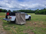 2021 Toyota Tacoma TRD offroad truck parked in a grassy area with a privacy tent and a dog nearby.