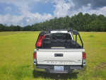2021 Toyota Tacoma TRD off-road truck parked in a grassy field, showing the cargo area and accessories.