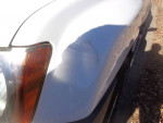 Close-up of a small dent on the front fender of a 2002 Nissan Xterra, showcasing vehicle condition.