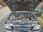 Engine compartment of a 2010 Ford Ranger XLT in army green, showing minor wear and well-maintained components.