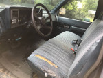 Interior view of a 1993 Chevrolet pickup truck, showcasing worn seat and dashboard features.