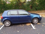 2008 Volkswagen Rabbit in blue, showing minor rust and a broken mirror cover, parked in an autumnal setting.
