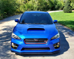 Front view of a 2017 Subaru WRX STI Limited in World Rally Blue parked on a scenic road.