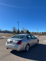 2005 Nissan Maxima parked outdoors, showcasing clean lines and new tires under a clear blue sky.