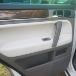 Interior door panel of a 2010 Volkswagen Touareg with leather trim and control switches