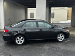 Side view of a 2013 Toyota Corolla LE for sale, showcasing its clean body and modern design.