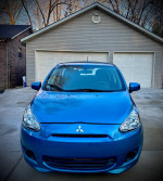 Front view of a blue 2015 Mitsubishi Mirage parked in a driveway, showing its low mileage and good condition.